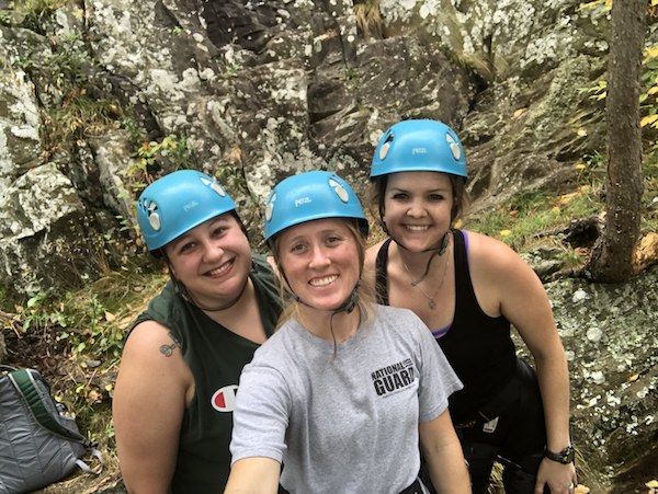 three people smiling wearing helmets after rock climbing